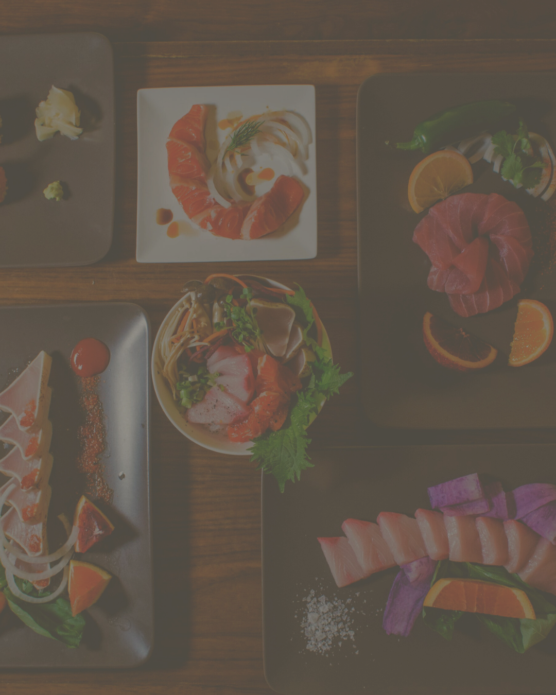 Assortment of fresh sashimi and sushi plates arranged on a wooden table for a pairing event.