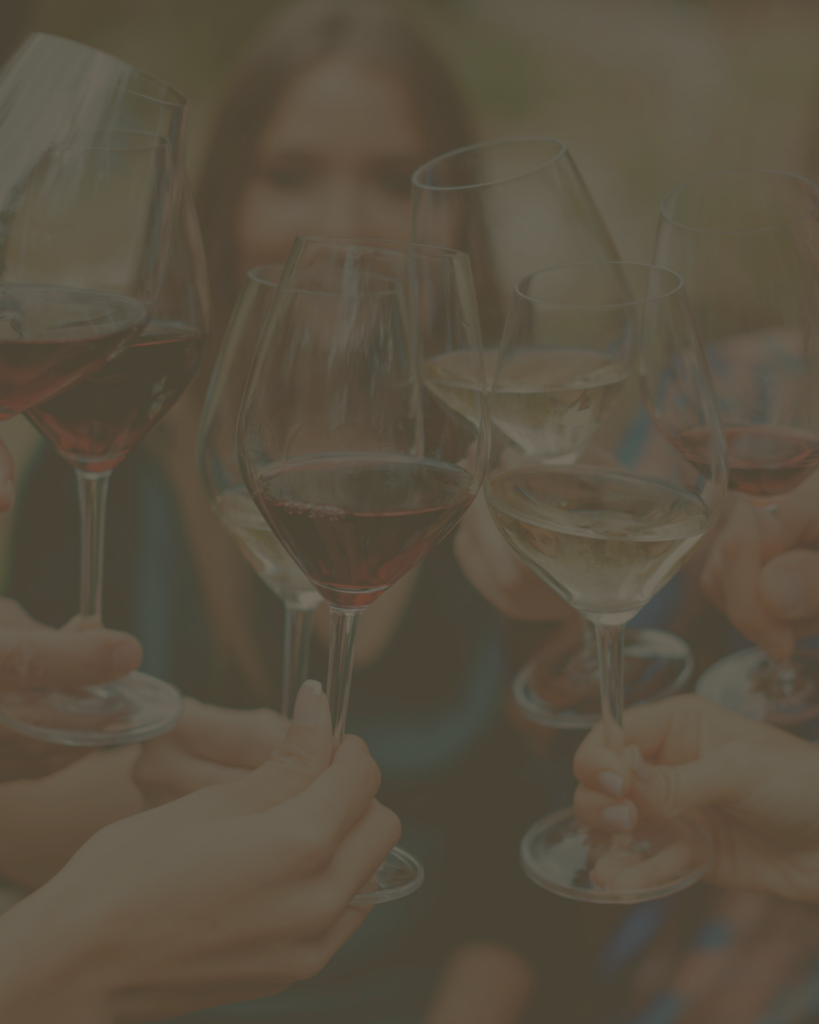 Close-up of guests toasting with red and white wine glasses at an outdoor event.