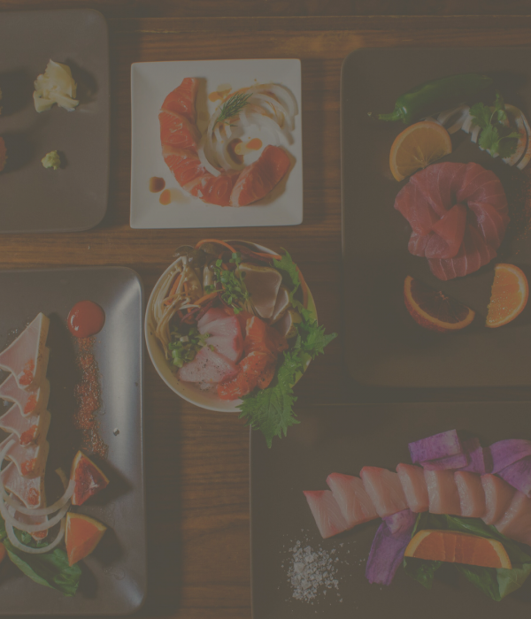 Assortment of fresh sashimi and sushi plates arranged on a wooden table for a pairing event.